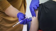 En persons arm blir stucken med en spruta med vaccin. 