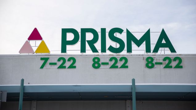Large signage on the top of a hypermarket that reads PRISMA and the hours of operation.