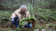 Ari Karhilahti tutkii sammalkasvustoa kaatuneessa puussa  Mälikkälän metsässä.