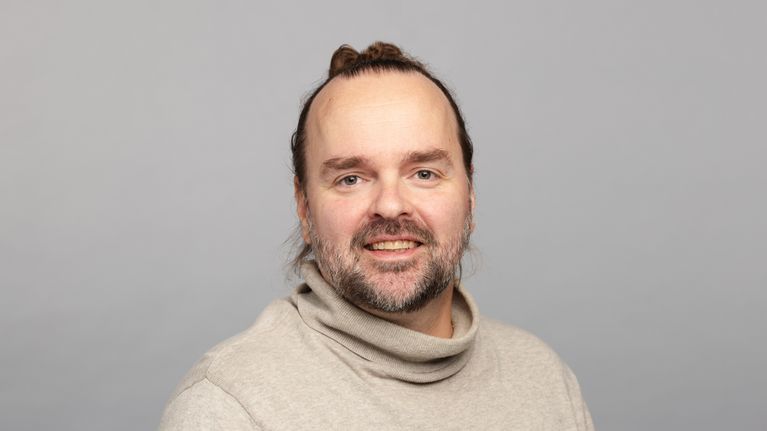 Jaakko Lempinen katsoo kameraan vaaleassa paidassa.