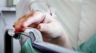 Närbild av en hand i sjukhusmiljö. Patienten får droppbehandling.