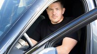 Jori Andberg istuu autossa kuskin paikalla pukeutuneena mustaan t-paitaan.