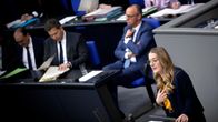 Katharina Dröge puhuu puhujakorokkeella, takana istuu  Friedrich Merz.