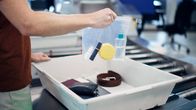 Käsi pitelee lentokentän turvatarkastuksessa minigrip-pussia, jossa on nesteitä.