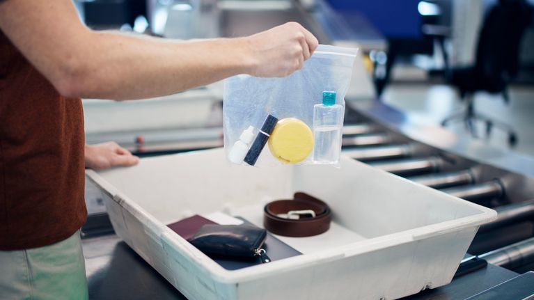 Käsi pitelee lentokentän turvatarkastuksessa minigrip-pussia, jossa on nesteitä.