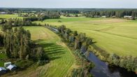 Joki virtaa maalaismaiseman läpi. 