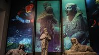 Välimeren syvyyksistä löydetyt harvinaiset patsaat ja keramiikkaesineet esillä museossa ja taustalla isoja valokuvia joissa esineet ovat meressä.