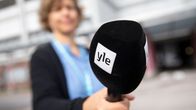 En redaktör håller en Yle-mikrofon. 