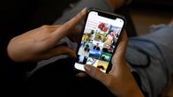 En person har Instagram öppet på telefonen. Bara händerna och famnen syns.