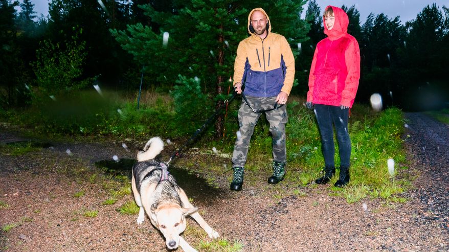 Titi-koira vetää hihnassa Tapiota perässään. Kaisa katsoo vieressä ja nauraa.