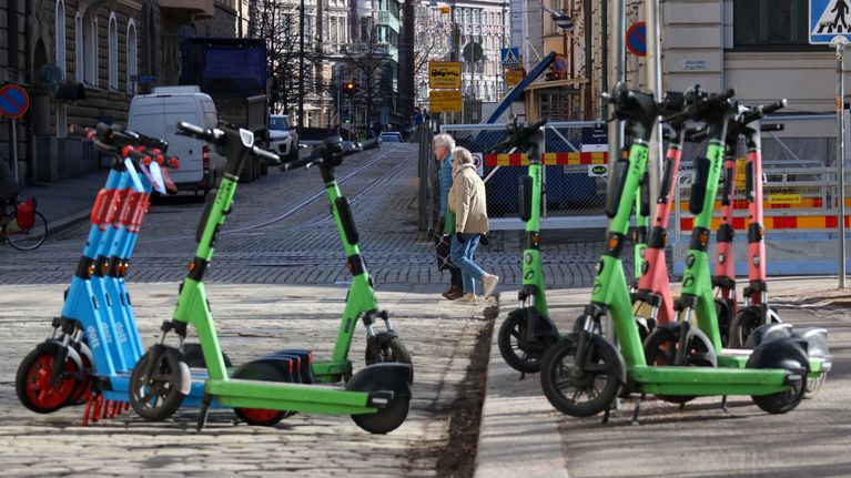 Electric scooters parked on the road and pavement.