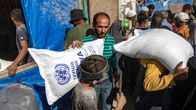 Kuvassa kaksi miestä kantavat jauhosäkkejä YK:n palestiinalaispakolaisten avustusjärjestön UNRWA:n  avustuskeskuksessa Khan Yunisissa Gazassa. 