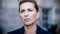 Henkilö, joka on pukeutunut tummansiniseen bleiseriin ja kultaisiin korvakoruihin. 