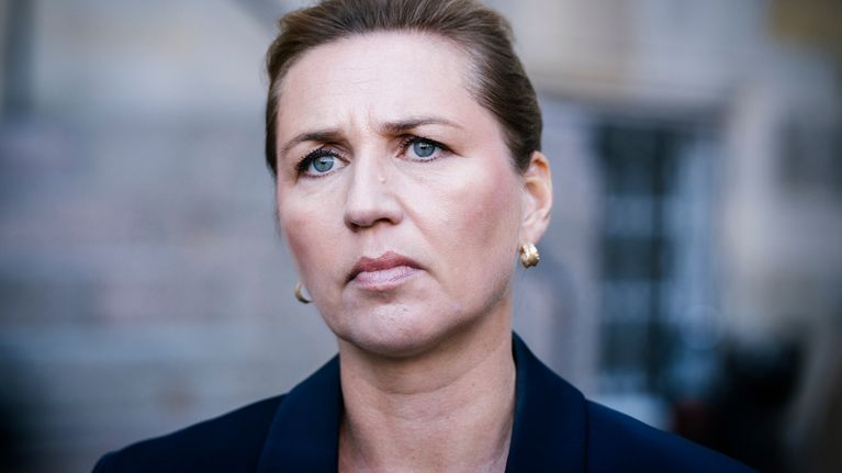 Henkilö, joka on pukeutunut tummansiniseen bleiseriin ja kultaisiin korvakoruihin. 