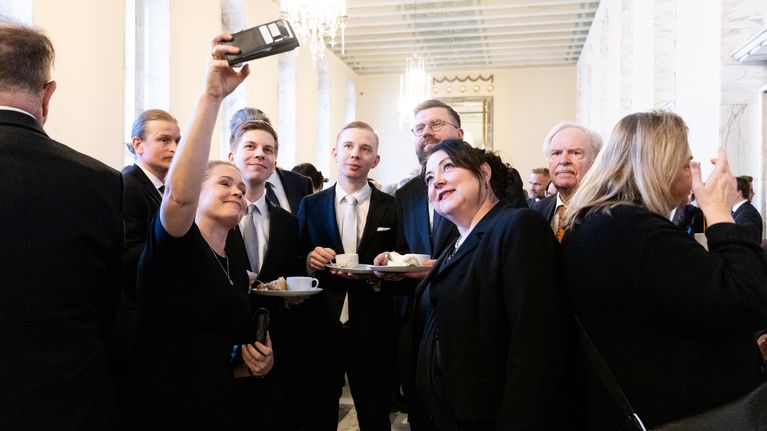 Ryhmä henkilöitä ottaa selfietä kakkukahvit kädessä.
