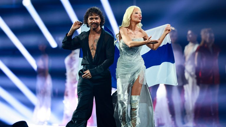 Pete Parkkonen och Linda Lampenius på scenen med Finlands flagga. 