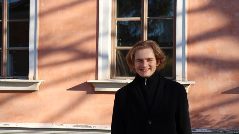 Puolalaispianisti Piotr Pawlak kuvattuna Hakasalmen huvilan edustalla. Hän hymyilee ja katsoo hieman kuvaajan ohi.