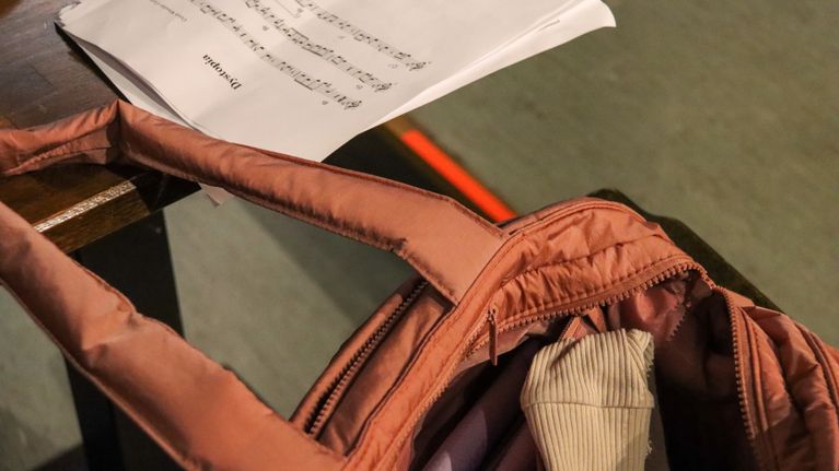 Hoitolaukku ja nuotit pöydällä viittaavat vauvanhoidon ja muusikontyön yhdistämiseen.