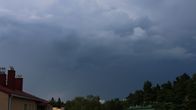 Dark rain clouds filling the sky. Rooftops and trees are seen in the bottom corners.