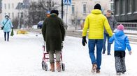 Photo shows people walking on a snow-covered street.
