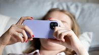 Photo shows a person looking at a phone screen.
