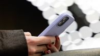 A person's hands holding a phone with a lilac phone case.
