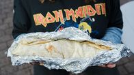 Lähikuva foliokääreessä olevasta kebabrullasta. Sitä pitelevän henkilön t-paidan rintamuksessa lukee  Iron Maiden.