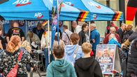 Sinisenturkoosit AfD-kirjaimin varustetut telttakatokset, joiden ympärillä paljon eri-ikäisiä ihmisiä ja Ulrich Siegmund -vaalijuliste.