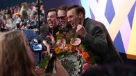 Jakob Norrgård, Axel Åhman ja Kevin Holmström hurraavat kameroiden kuvatessa heitä, kukkakimput käsissä.