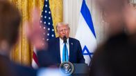 Donald Trump puhumassa lehdistötilaisuudessa Yhdysvaltain ja Israelin lippujen edessä.