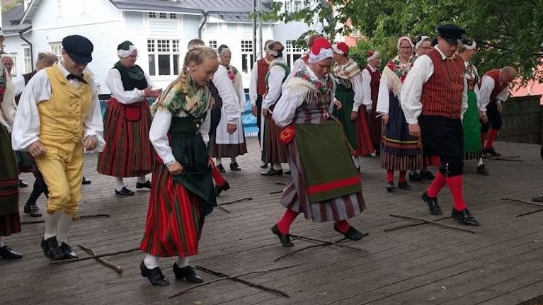 Folkdansare uppträder med dansen Skinkompassen på en scen.