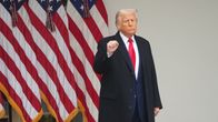 Donald Trump seisoo lippujen edessä toinen nyrkki koholla.