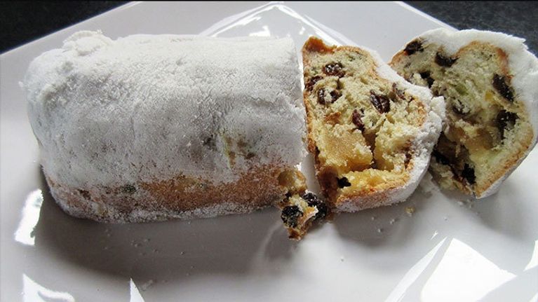 Stollen-kakku ja pari valmiiksi leikattua viipaletta valkoisella tarjoilulautasella.