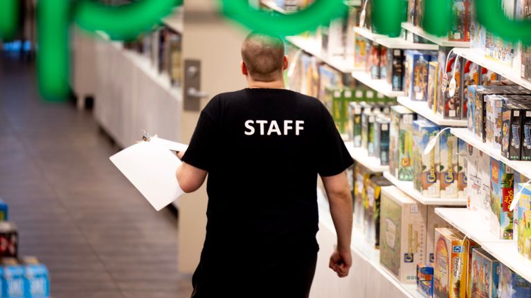 Kaupan työntekijä staff paita yllään kävelee kaupassa.