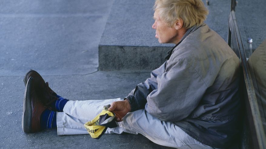 Mies istuu maassa kerjäämässä rahaa lippalakkiinsa vuonna 1991.