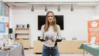 Linda Joronen seisoo ja katsoo kameraan pidellen tekstiilikuituja käsissään. 