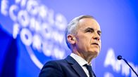 Mark Carney puhuu mikrofoniin sinisessä puvussa ja kravatissa. Taustakangas on sininen ja siinä on teksti: World Economic Forum.