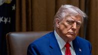 Donald Trump sinisessä puvuntakissa istuu tuolissa.