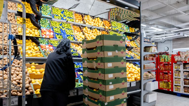 A grocery store employee stocks up the fruit section.