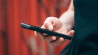 Close-up photo of a woman's hand using a smartphone, seen from the side. 