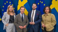 Två kvinnor och två män står på rad med svenska flaggor och EU-flaggor i bakgrunden. Alla fyra är formellt klädda.