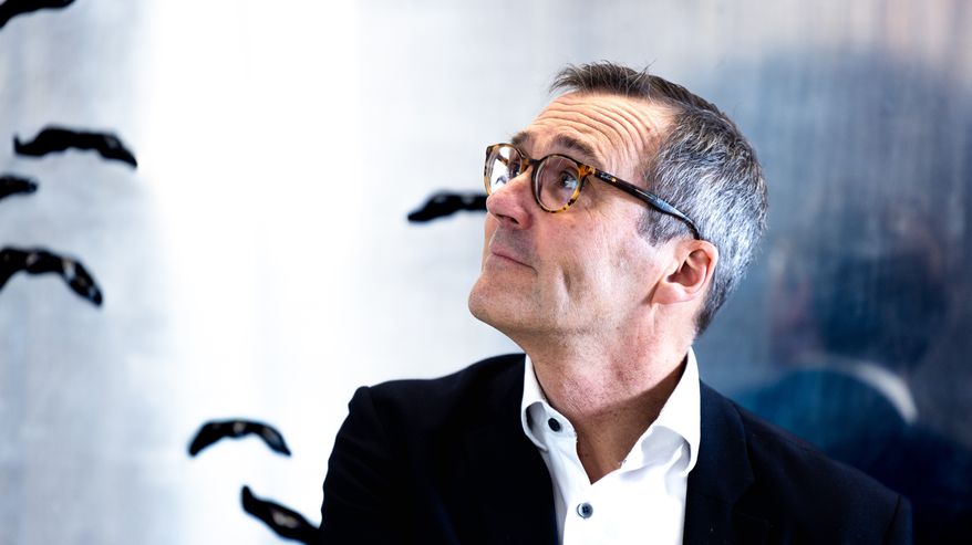 Mikko Kautto katsoo hieman ylöspäin sivuprofiilissa taustalla näkyy hieman taideteosta seinällä.