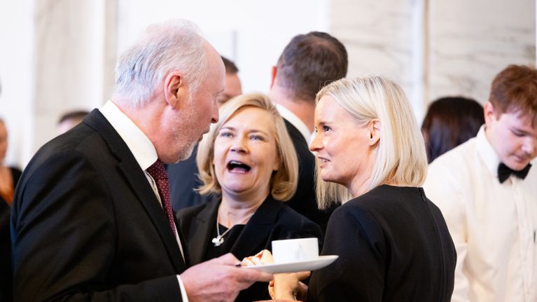 Kolme henkilö keskustelevat hymyssä suin.
