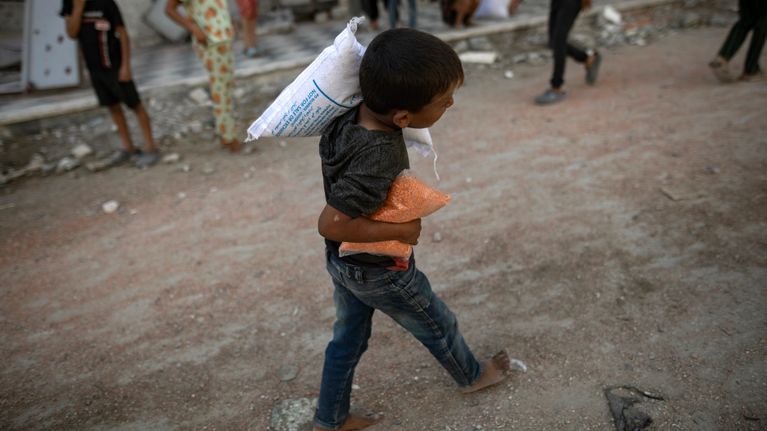 Palestiinalaispoika kantaa Khan Yunisiin lauantaina tullutta ruoka-apua.
