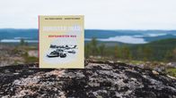 Ihmisten Inari - kohtaamisten maa -kirja tunturin laella kiven päällä, taustalla Inarinjärvi.