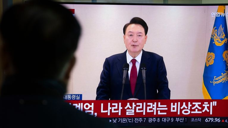 Etelä-Korean presidentti Yoon Suk-yeol puhuu televisiossa. Etualalla oikealla näkyy ihmisen hahmo katsomassa lähetystä.