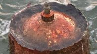 A rusty metallic object on the surface of the sea.
