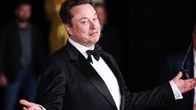 Elon Musk elehtii käsillään puku päällä.