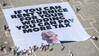 Ett stort plakat utbrett på ett torg i Venedig. Texten lyder "If you can rent Venice for your wedding you can pay more tax".