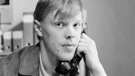 Vesa-Matti Loiri puhuu lankapuhelimeen ja katsoo kameraan.